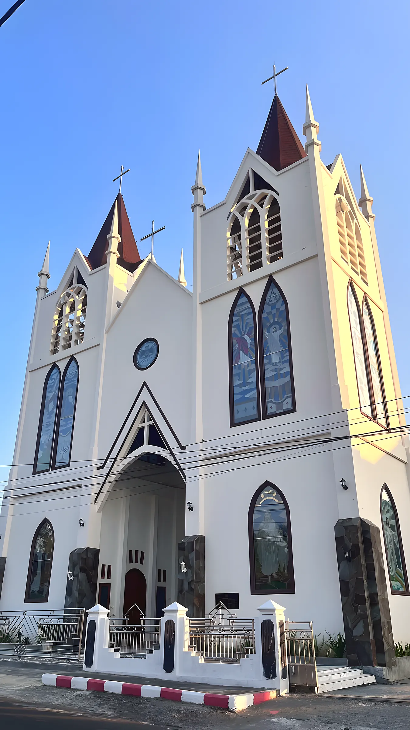 Gereja berwarna putih dengan menara runcing dan jendela kaca patri